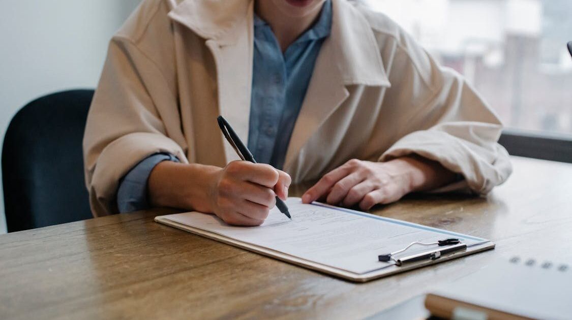 Person schreibt auf Formular, Symbol für Auskunftsantrag und Petition