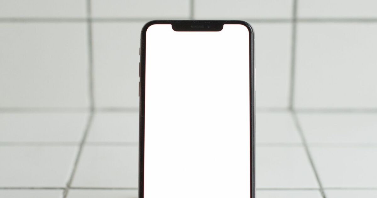 Smartphone mit leerem Bildschirm auf einem Holzhalter, Symbolbild