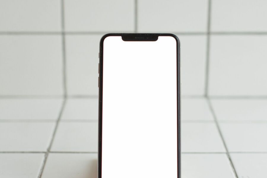 Smartphone mit leerem Bildschirm auf einem Holzhalter, Symbolbild